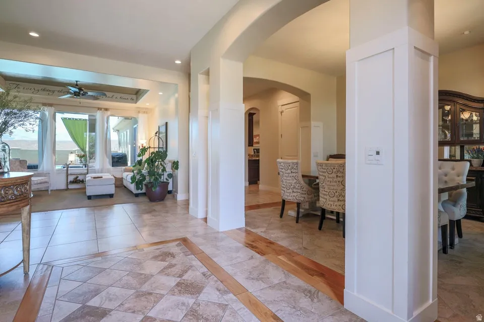 Tile flooring with wood-finish inlay, arched doorways, white trim, recessed lighting, and large picture windows