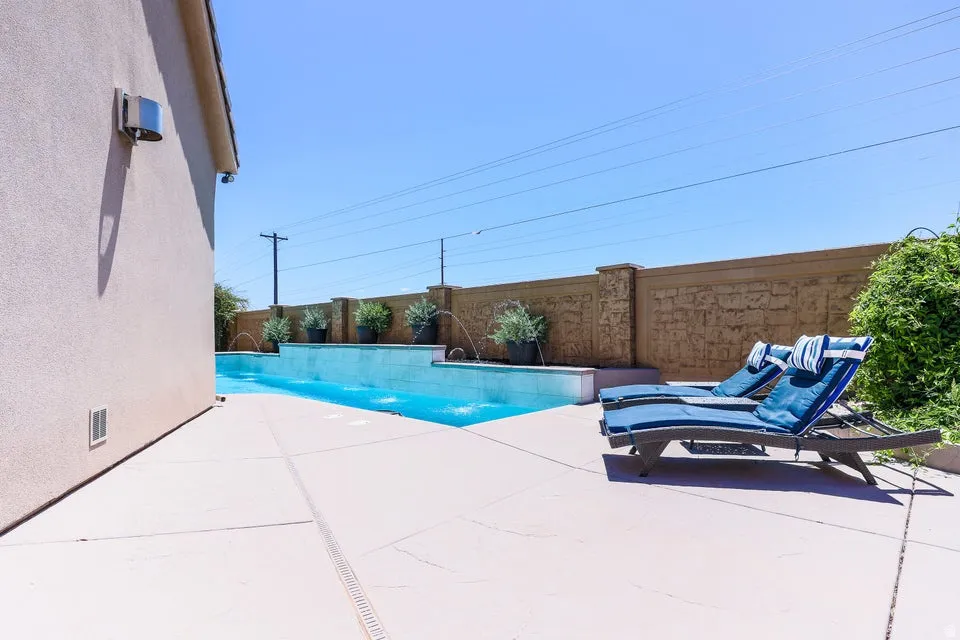 Expansive outdoor patio featuring a rectangular swimming pool with integrated water features