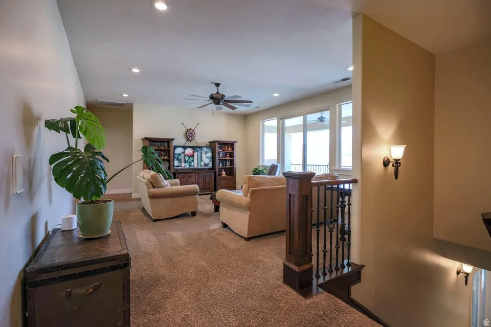 Upper-level living area featuring neutral carpeting, recessed lighting, and a ceiling fan