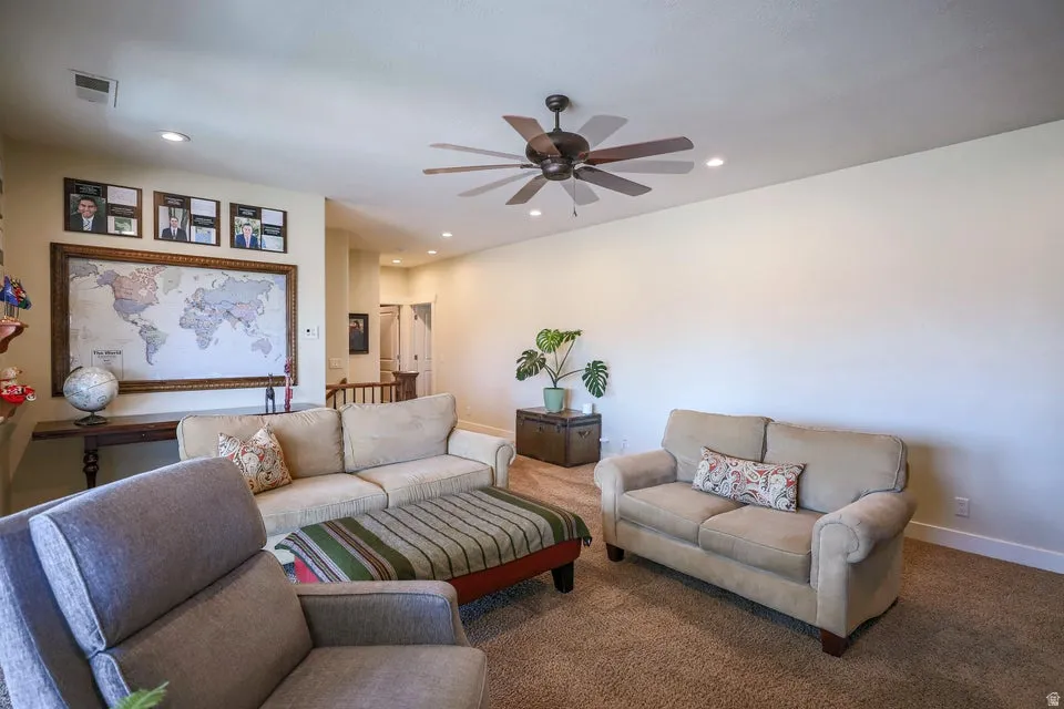 Spacious living area featuring neutral-toned walls, recessed lighting, and a dark-toned ceiling fan