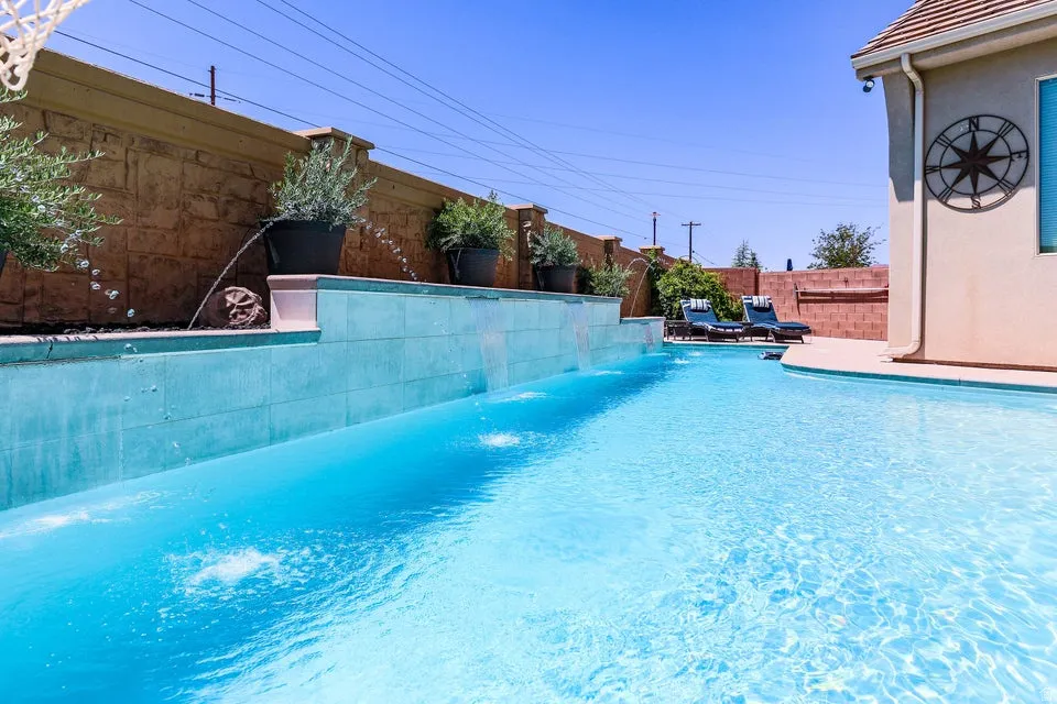 In-ground swimming pool featuring multiple water features, a built-in spa, and surrounding hardscaping