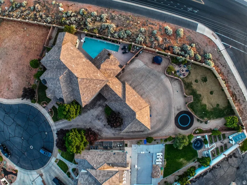 Expansive property featuring a multi-gabled roofline, concrete driveways, an in-ground swimming pool, and a dedicated fire pit area