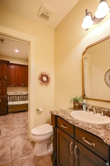 Bathroom featuring a dark wood vanity with a light-colored countertop, an undermount sink, and a decorative mirror