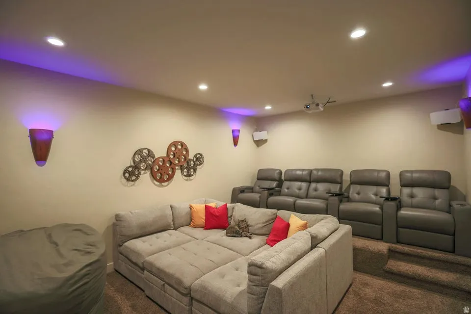 Dedicated media room featuring tiered seating, recessed ceiling lighting, and wall-mounted sconces