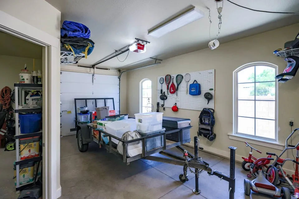 Spacious garage featuring a concrete floor, two arched windows with white trim, and a built-in overhead storage rack