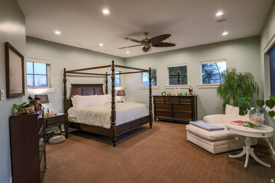 Spacious bedroom featuring light-colored walls, recessed ceiling lighting, and multiple windows with white trim