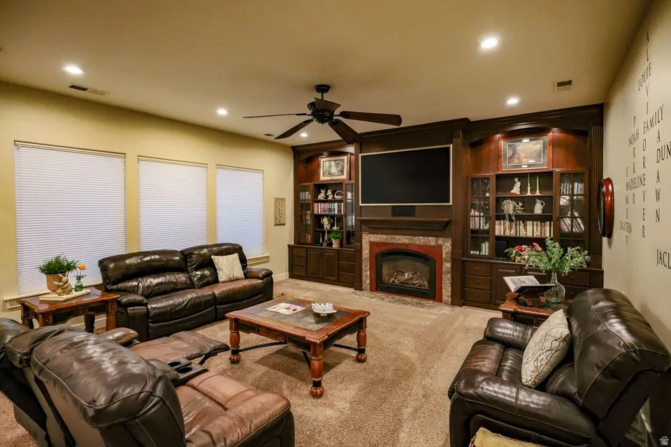 Living area featuring a floor-to-ceiling custom wood built-in entertainment center with integrated shelving, a fireplace with stone surround, and recessed lighting