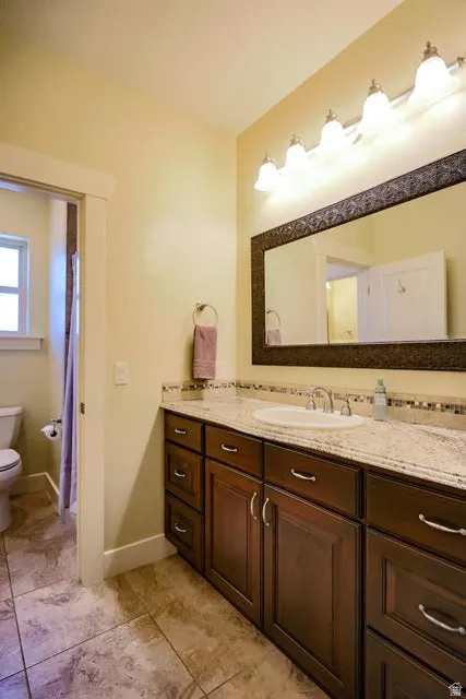 Bathroom vanity featuring dark wood cabinetry, a light-toned granite-style countertop, and an integrated white porcelain sink