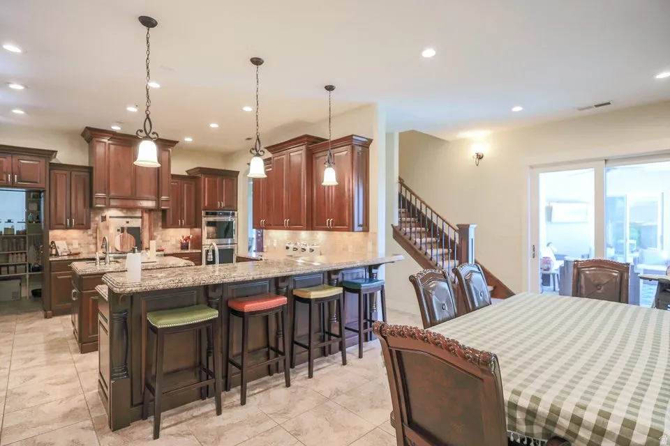 Spacious kitchen featuring dark wood cabinetry, a large kitchen island with seating, a secondary prep island, and integrated stainless steel appliances