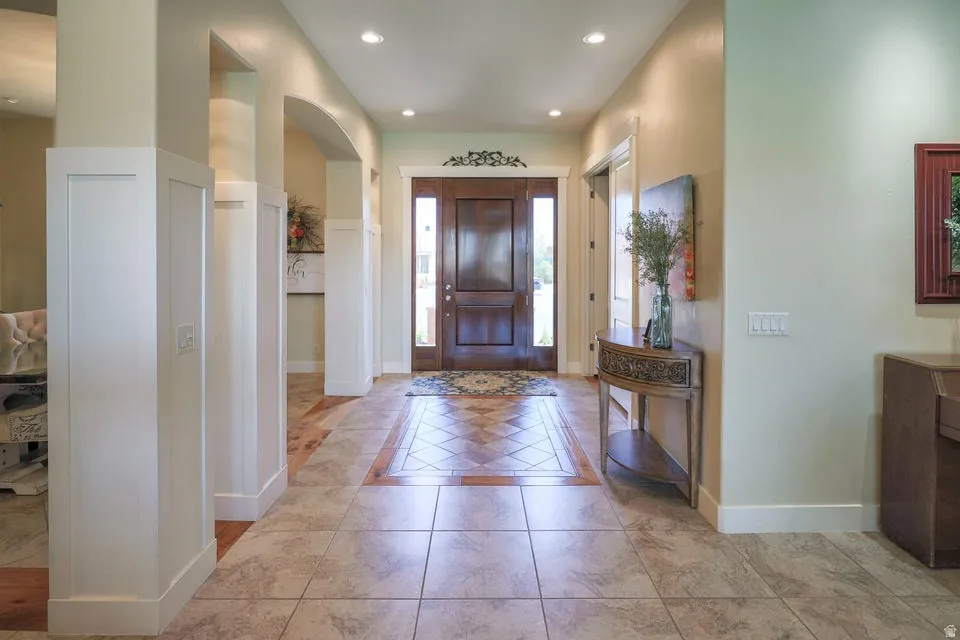 Entryway featuring a dark wood front door with sidelights, recessed lighting, and a combination of tile flooring and wood-finish flooring