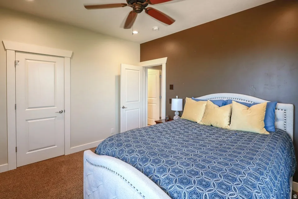 Carpeted room featuring a ceiling fan with integrated lighting, recessed lighting, and two panel doors with trim