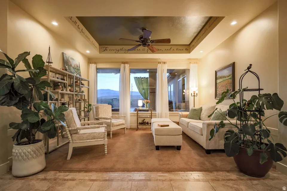 Recessed ceiling lighting illuminates a tray ceiling with a dark inset and ceiling fan