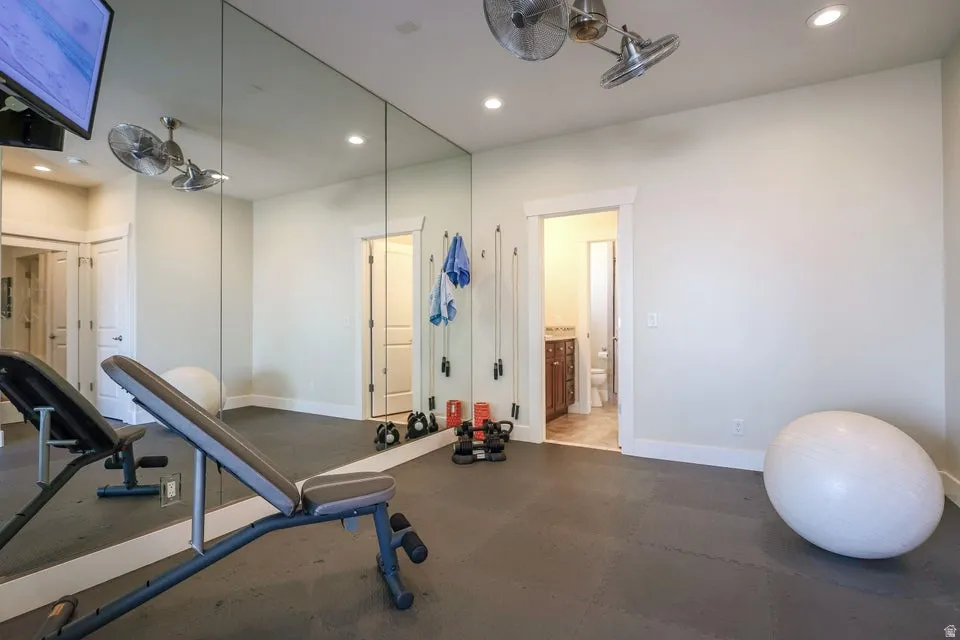 Dedicated fitness space featuring full-wall mirrors, recessed lighting, and durable rubber flooring