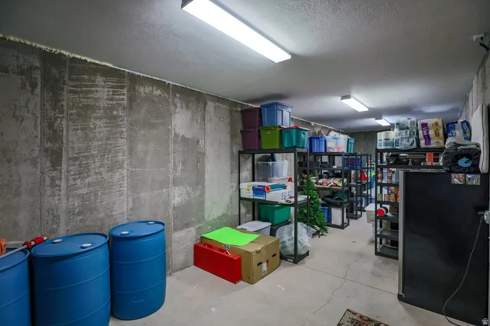 Substantial unfinished basement space featuring exposed concrete walls, a concrete floor, and overhead fluorescent lighting