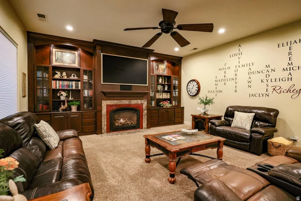 Living area featuring built-in wood cabinetry, a fireplace with a stone surround, and recessed lighting