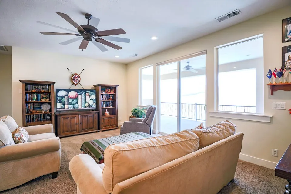 Spacious living area featuring a multi-blade ceiling fan, recessed lighting, and soft carpet flooring