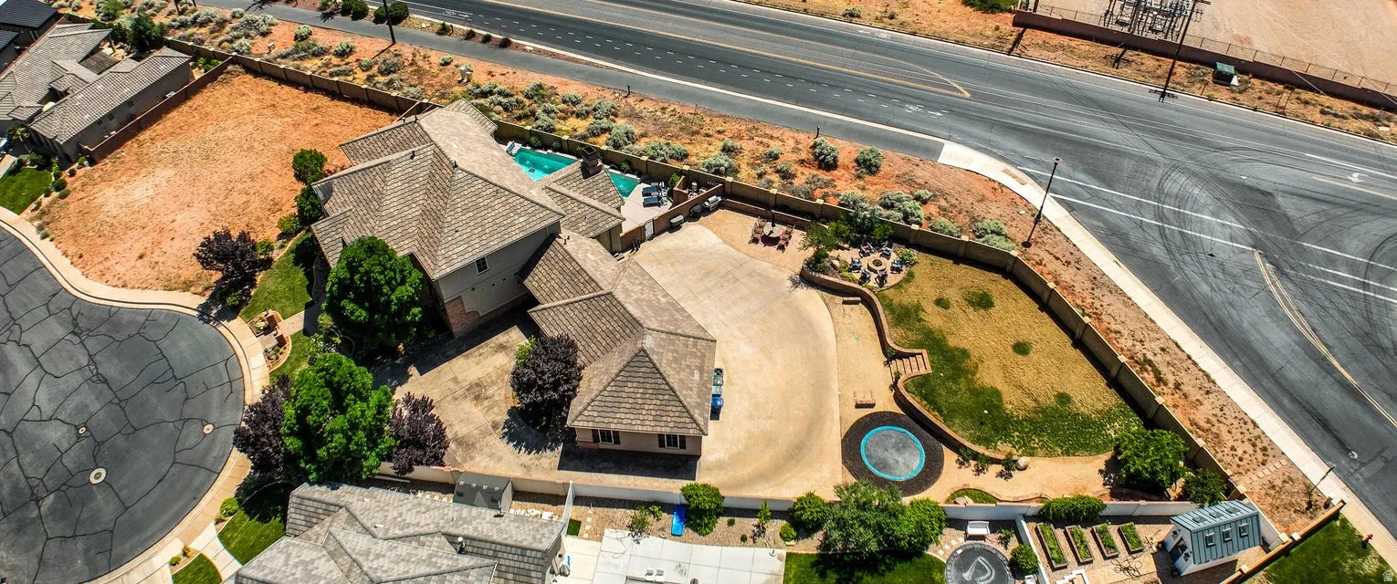 Aerial view showcasing the property's expansive footprint, featuring a multi-level roofline, a swimming pool, a circular drive, and a retaining wall with integrated landscaping