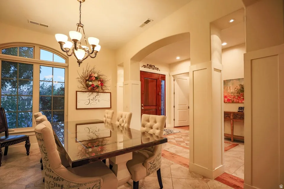 Elegant dining area featuring a prominent arch window with an arched transom, a chandelier, and tile flooring
