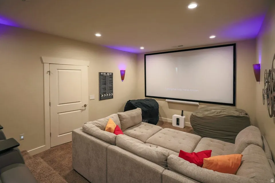 Dedicated media room featuring a large projection screen, recessed ceiling lighting, and wall sconces