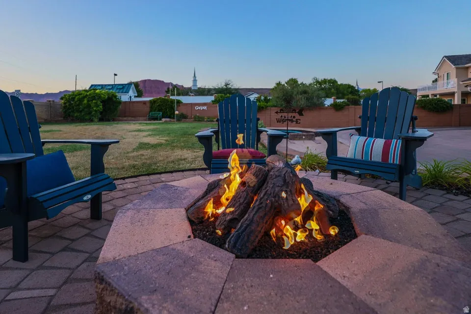 Paver patio featuring a built-in fire pit with log accents and ample surrounding space