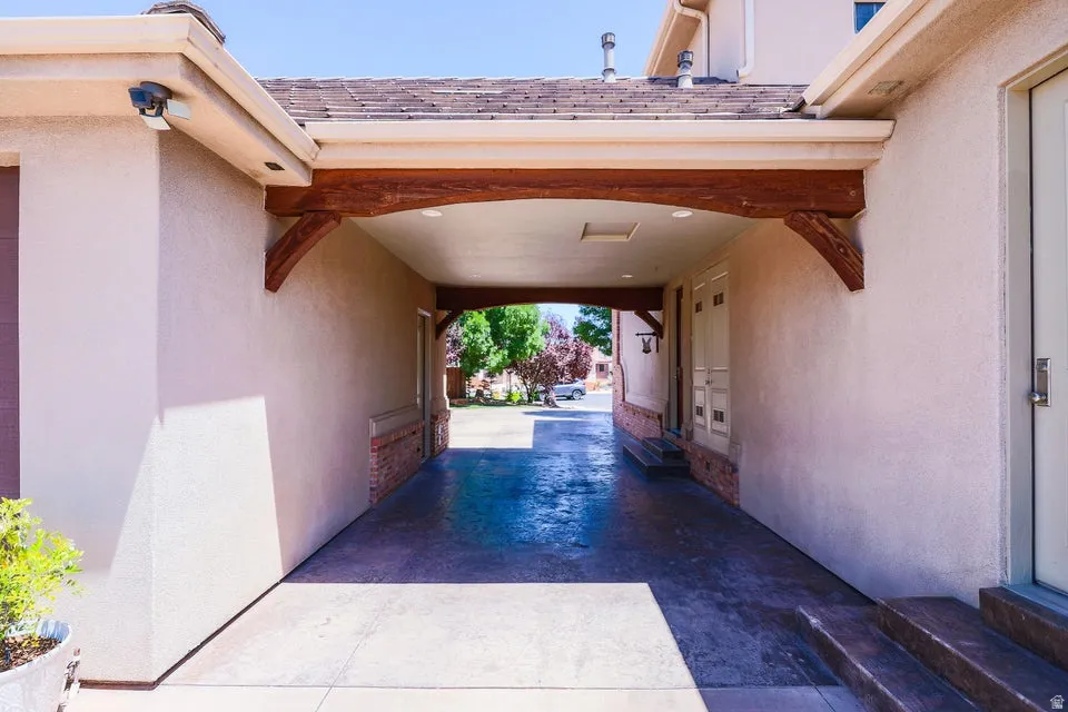 Covered entryway featuring a decorative wood beam, stucco exterior, and concrete flooring
