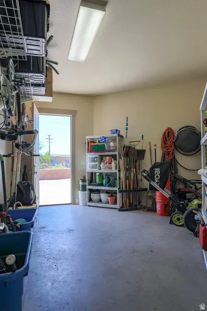 Spacious garage featuring a concrete floor, overhead fluorescent lighting, and a pedestrian door for outdoor access