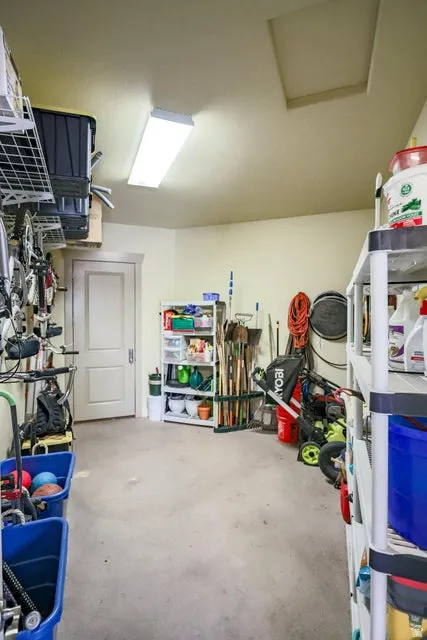 Spacious utility area featuring a wide concrete floor, a fluorescent ceiling light fixture, and a white interior door