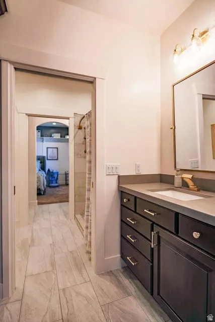 Contemporary bathroom featuring a dark wood vanity with a light countertop, a built-in rectangular sink, and a gold-tone faucet