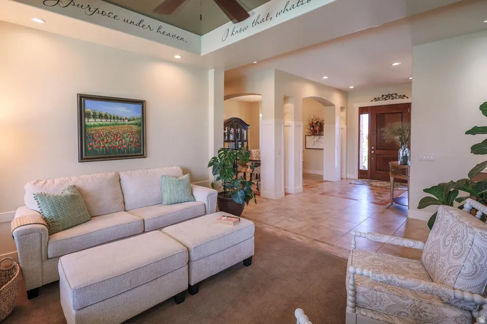Spacious interior featuring a tiled entryway, carpeted living area, arched doorways, recessed lighting, and a dark wood paneled entry door
