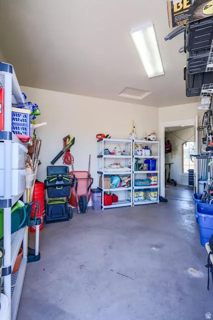 Spacious garage featuring a durable concrete floor, overhead fluorescent lighting, and ample storage shelving