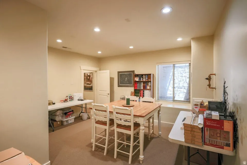 Carpeted interior space with recessed lighting and a window featuring horizontal blinds