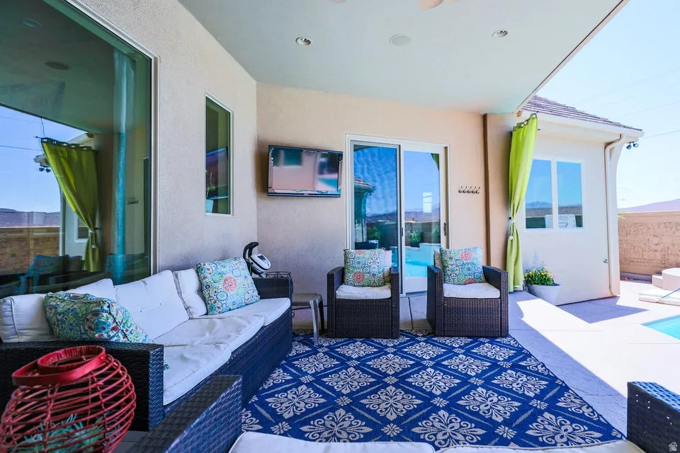Covered outdoor patio with a patterned area rug, recessed lighting, and a wall-mounted display