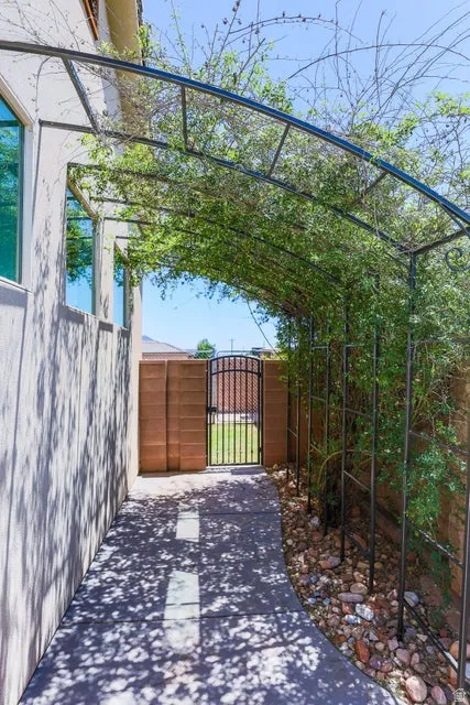 Covered walkway featuring an arched metal trellis with established greenery