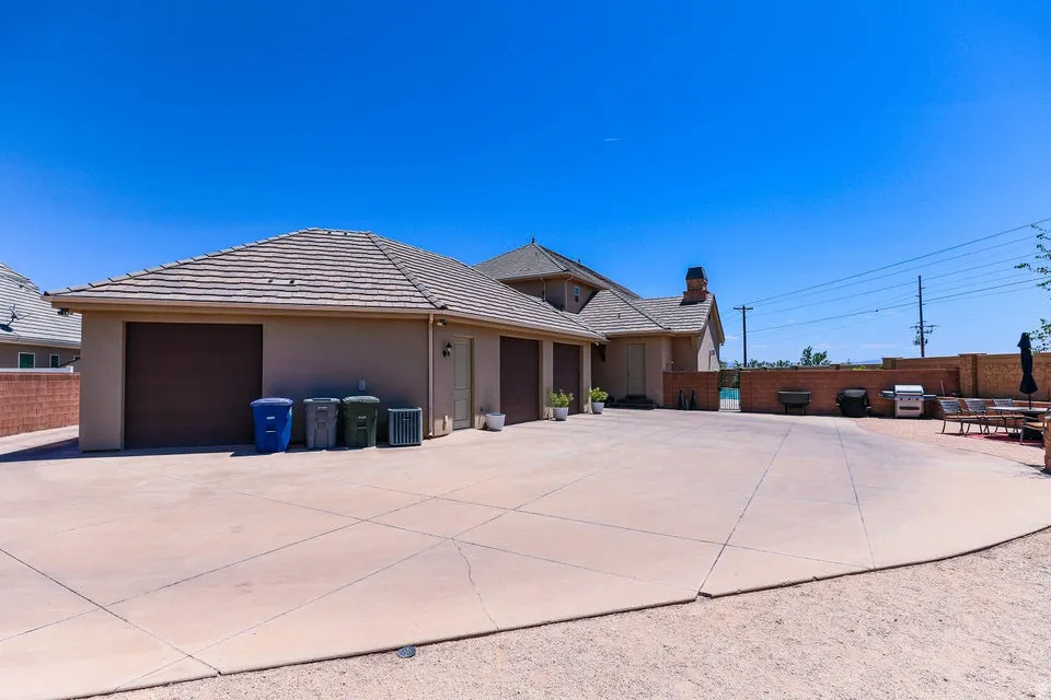 Expansive concrete driveway leading to a multi-car garage with brown doors