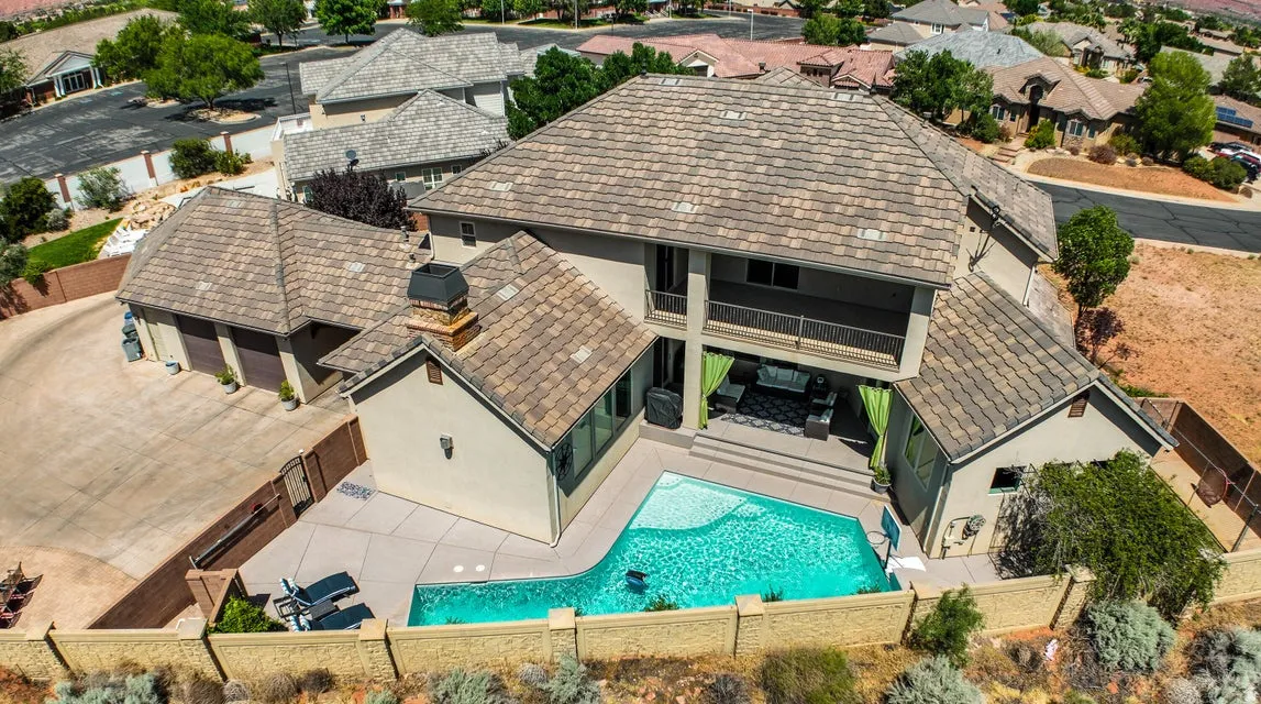 Outdoor entertainment space featuring a swimming pool, multiple patio areas, and a multi-car garage with an expansive driveway