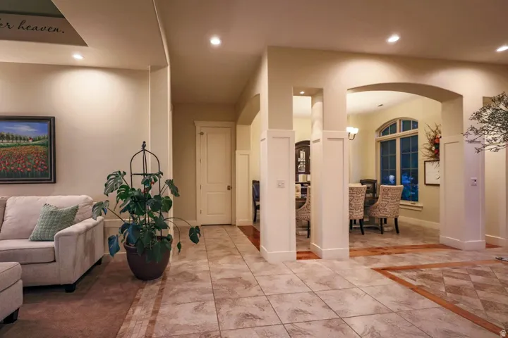 Expansive tiled flooring with accent border, arched doorway to dining area, recessed lighting, and white paneled walls