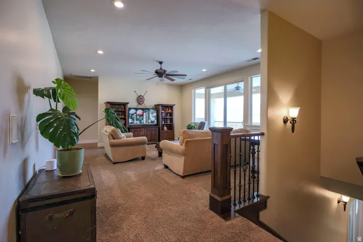 Upper-level living area featuring neutral carpeting, recessed lighting, and a ceiling fan