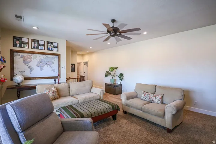 Spacious living area featuring neutral-toned walls, recessed lighting, and a dark-toned ceiling fan