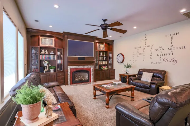 Living area featuring a floor-to-ceiling custom entertainment center with rich wood-finish cabinetry, integrated shelving, and a built-in fireplace with a red-toned surround