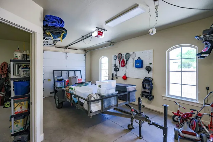 Spacious garage featuring a concrete floor, two arched windows with white trim, and a built-in overhead storage rack