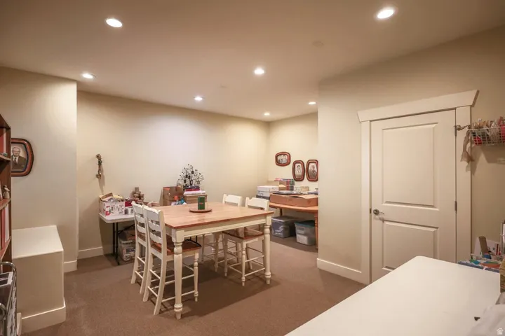 Recessed lighting illuminates this room, featuring neutral-toned walls and carpet flooring