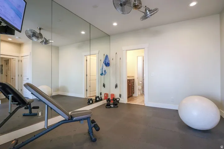 Dedicated fitness space featuring full-wall mirrors, recessed lighting, and durable rubber flooring