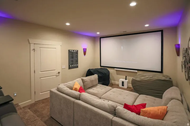 Dedicated media room featuring a large projection screen, recessed ceiling lighting, and wall sconces