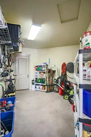 Spacious utility area featuring a wide concrete floor, a fluorescent ceiling light fixture, and a white interior door