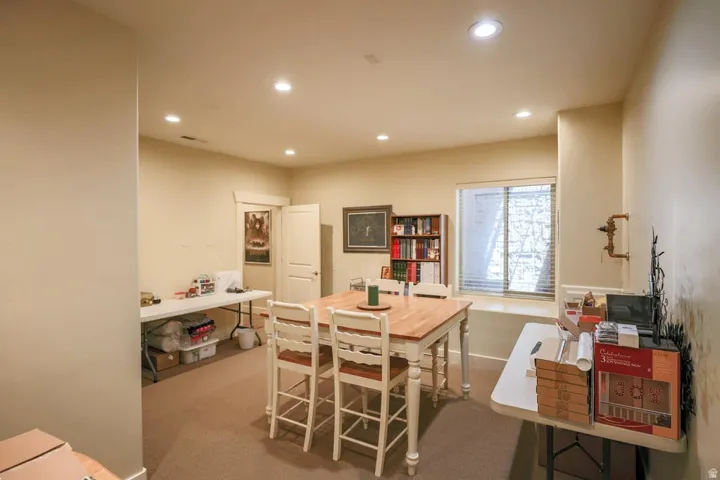 Carpeted interior space with recessed lighting and a window featuring horizontal blinds