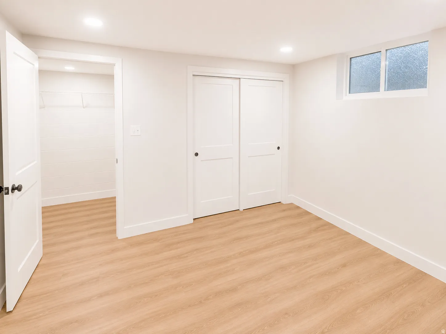 Room featuring light wood-finish flooring, recessed lighting, and a window with opaque glass