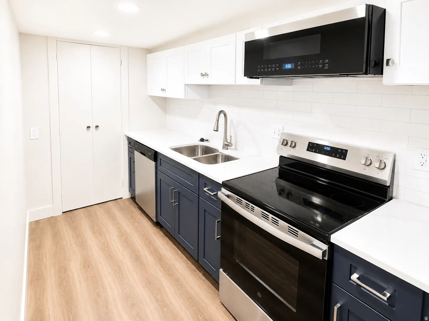 Contemporary kitchen featuring two-tone cabinetry, white countertops, and stainless steel appliances
