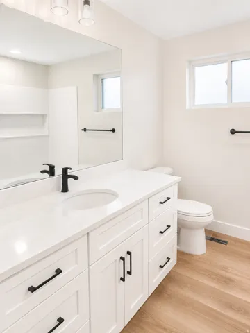 Bathroom featuring a white vanity with a solid surface countertop, an undermount sink, and matte black hardware