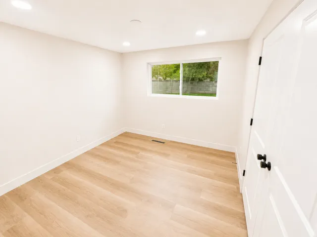 Bright interior space featuring light wood-finish flooring, recessed lighting, and a white interior door with black hardware