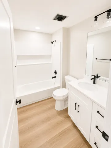 Bathroom featuring a white vanity with white countertop, integrated sink, and black hardware